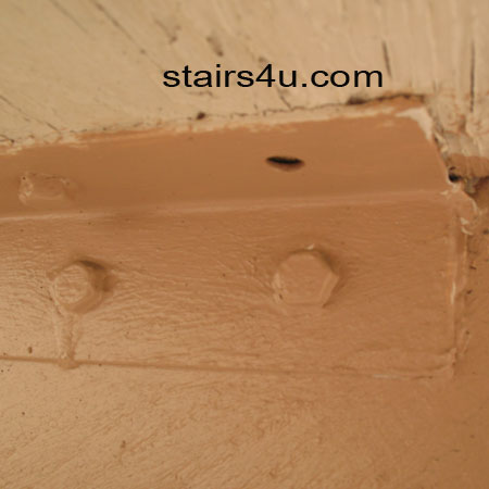 wood stairway with missing lag screw used to attach metal bracket to step