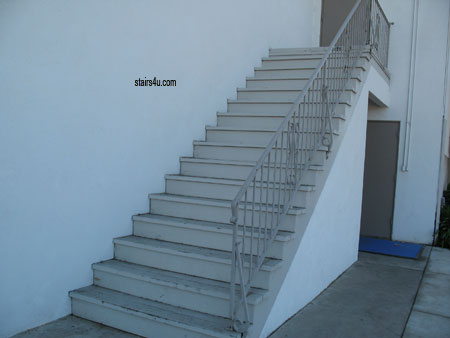 wood stairway next to stucco building and water leaks